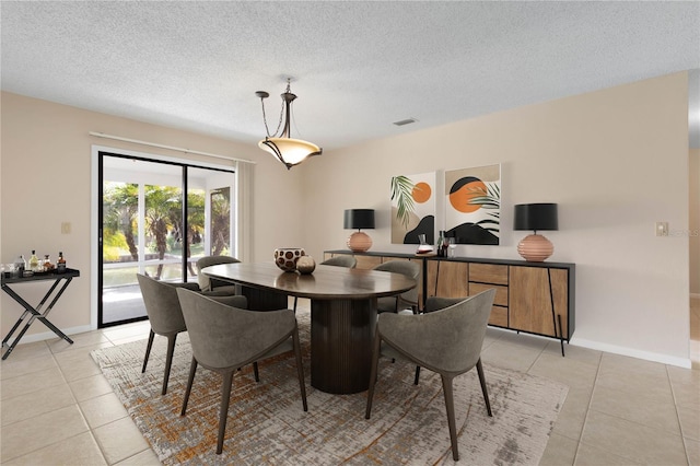 dining space with a textured ceiling, baseboards, and light tile patterned floors