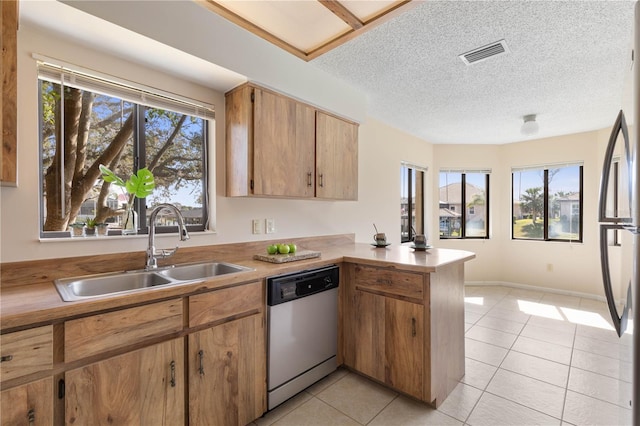 kitchen featuring stainless steel appliances, light countertops, visible vents, a sink, and a peninsula