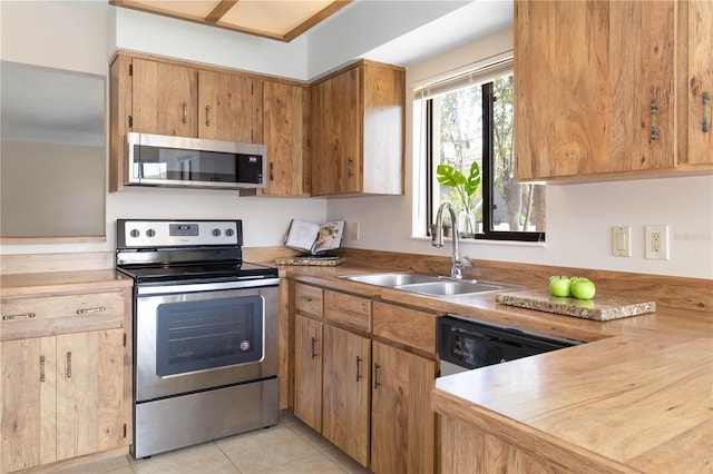 kitchen featuring light tile patterned floors, appliances with stainless steel finishes, light countertops, and a sink