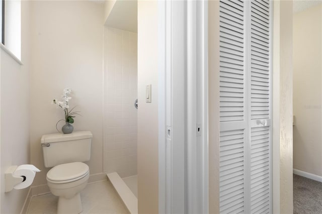 bathroom with baseboards, toilet, tile patterned floors, a shower stall, and a closet