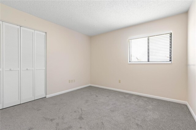 unfurnished bedroom featuring carpet floors, a closet, baseboards, and a textured ceiling