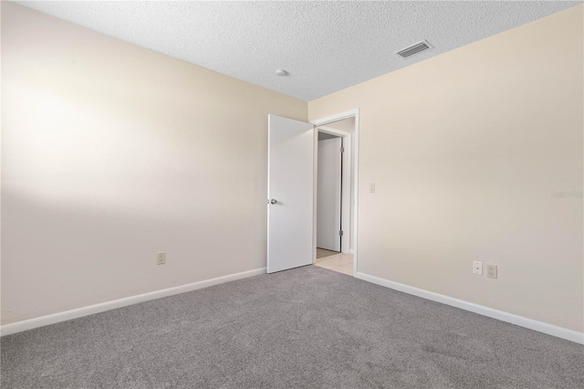 empty room featuring visible vents, baseboards, a textured ceiling, and light colored carpet