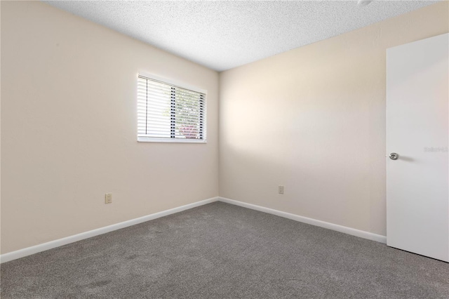 carpeted spare room featuring a textured ceiling and baseboards