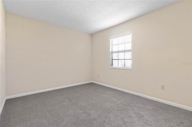 spare room featuring carpet flooring, a textured ceiling, and baseboards