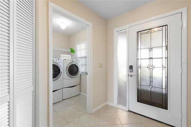 clothes washing area with washer and clothes dryer, light tile patterned flooring, a textured ceiling, laundry area, and baseboards