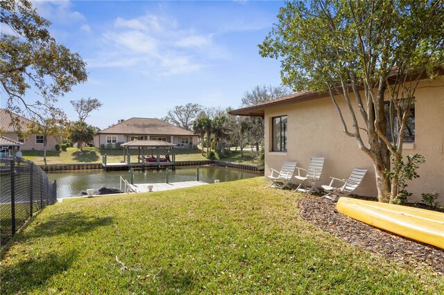 view of dock featuring a water view, a lawn, and fence