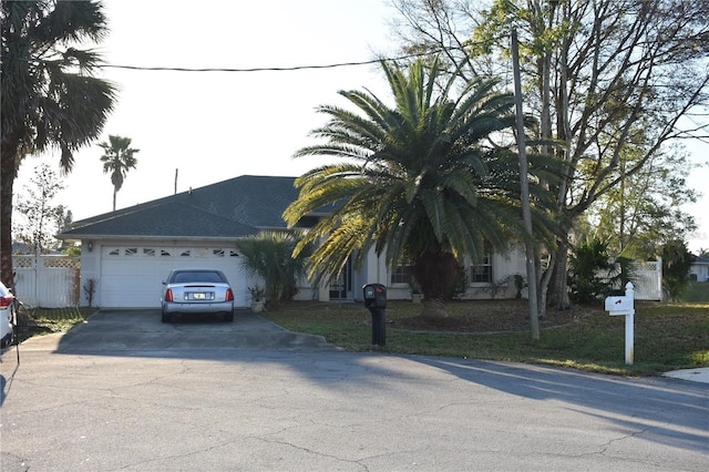 view of front of house featuring concrete driveway, an attached garage, and fence