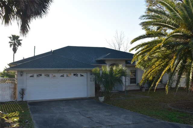 ranch-style home featuring concrete driveway, fence, an attached garage, and stucco siding