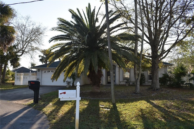 obstructed view of property with driveway, an attached garage, and fence