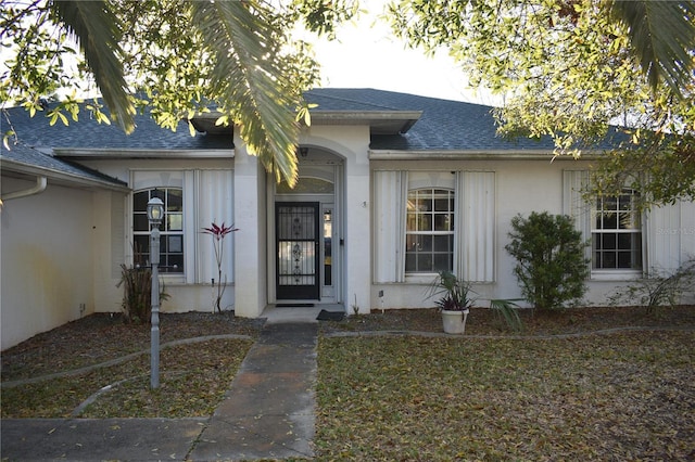 property entrance featuring roof with shingles and stucco siding