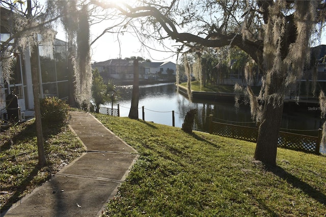 view of yard with a water view, a boat dock, and fence