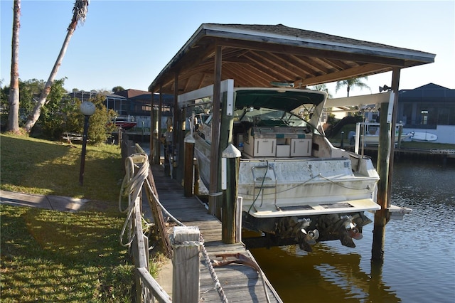 dock area with a water view, a yard, and boat lift