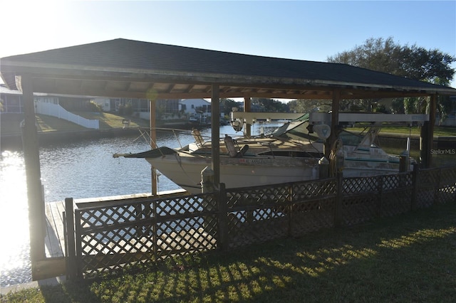 dock area with a water view, boat lift, and fence