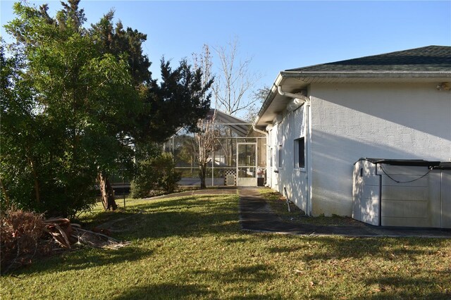 view of home's exterior featuring glass enclosure and a yard