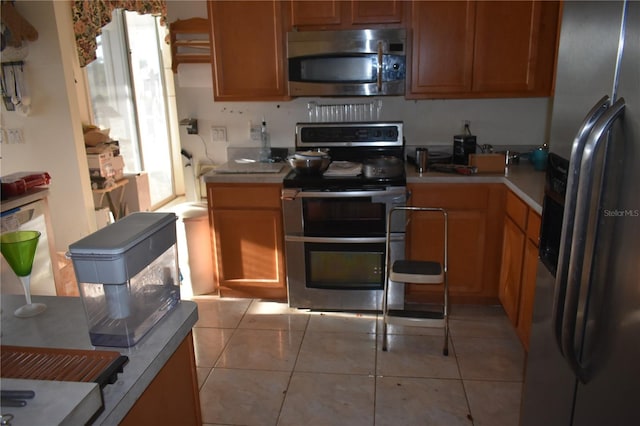 kitchen with stainless steel appliances, light tile patterned flooring, and light countertops