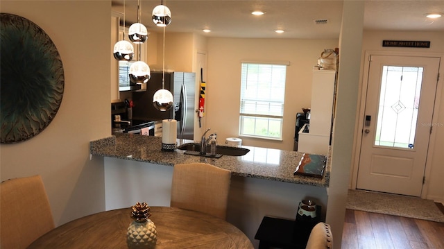 kitchen with visible vents, electric range, a sink, wood finished floors, and dark stone counters