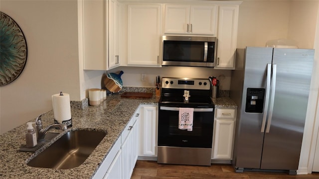 kitchen featuring light stone counters, appliances with stainless steel finishes, dark wood-type flooring, white cabinetry, and a sink