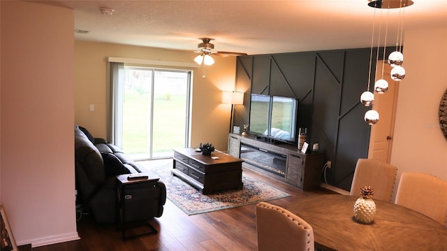 living room with ceiling fan and dark wood-type flooring