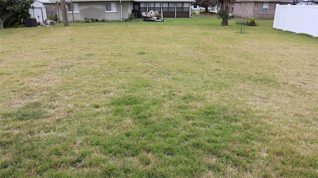 view of yard featuring an outbuilding, central AC, fence, and a storage shed