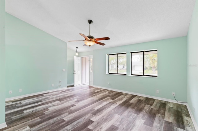 unfurnished room featuring ceiling fan, baseboards, vaulted ceiling, and wood finished floors