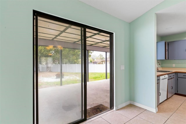 doorway featuring light tile patterned floors, baseboards, and a sink