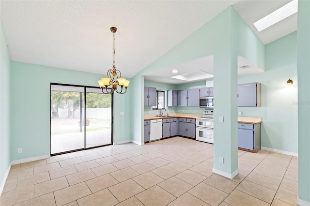 kitchen featuring light tile patterned floors, gray cabinetry, white appliances, a sink, and light countertops