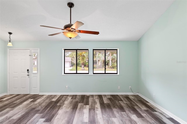 spare room featuring ceiling fan, baseboards, and wood finished floors