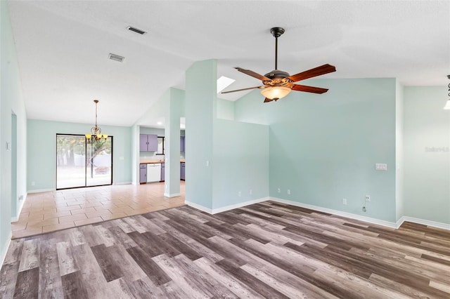 unfurnished living room featuring baseboards, visible vents, wood finished floors, and ceiling fan with notable chandelier