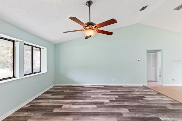 empty room with visible vents, ceiling fan, vaulted ceiling, wood finished floors, and baseboards