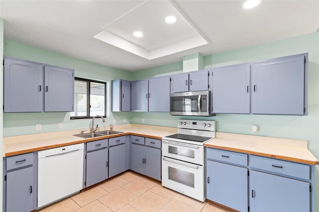 kitchen with recessed lighting, a raised ceiling, light tile patterned flooring, a sink, and white appliances