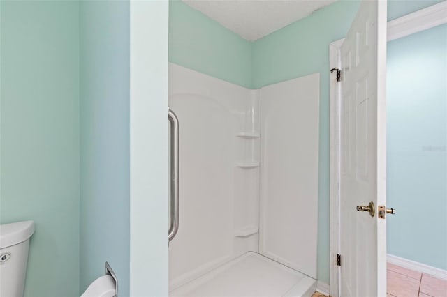 bathroom featuring a textured ceiling, walk in shower, toilet, and tile patterned floors