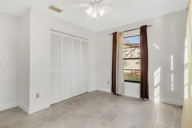 unfurnished bedroom with light tile patterned floors, baseboards, visible vents, ceiling fan, and a closet