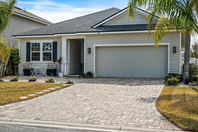 view of front facade featuring decorative driveway, roof with shingles, and an attached garage