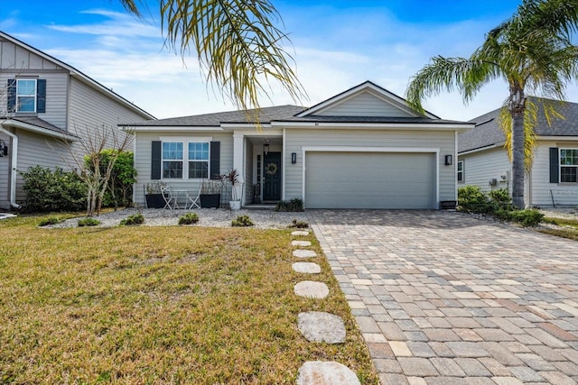 view of front of home with a garage, a front yard, and decorative driveway