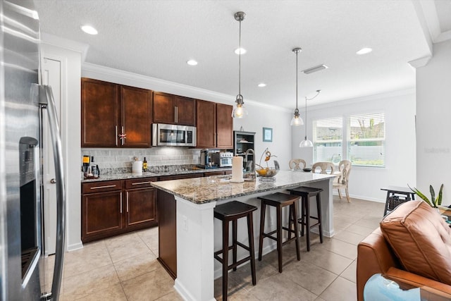 kitchen featuring stainless steel appliances, visible vents, a kitchen breakfast bar, ornamental molding, and decorative backsplash