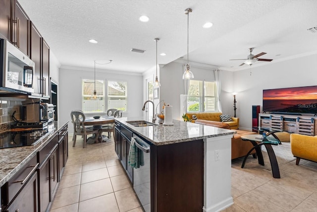 kitchen with light tile patterned floors, stainless steel appliances, a sink, ornamental molding, and light stone countertops