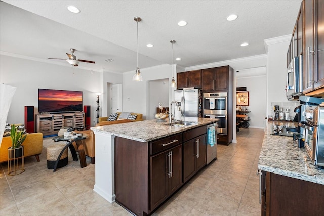 kitchen featuring appliances with stainless steel finishes, light stone counters, crown molding, dark brown cabinets, and a sink