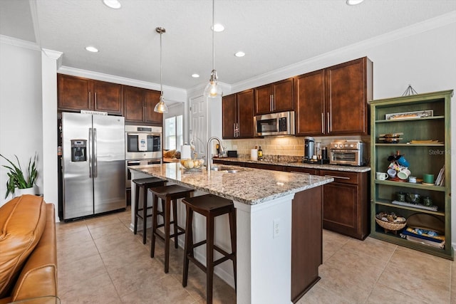 kitchen featuring stainless steel appliances, a sink, light stone counters, and ornamental molding