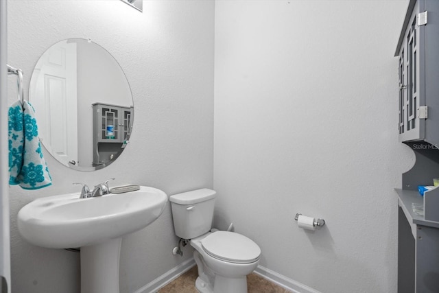 bathroom with tile patterned flooring, baseboards, and toilet