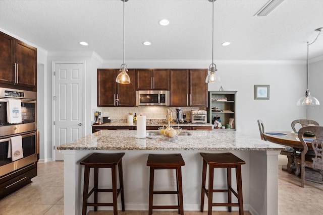 kitchen featuring tasteful backsplash, appliances with stainless steel finishes, dark brown cabinets, and a breakfast bar area