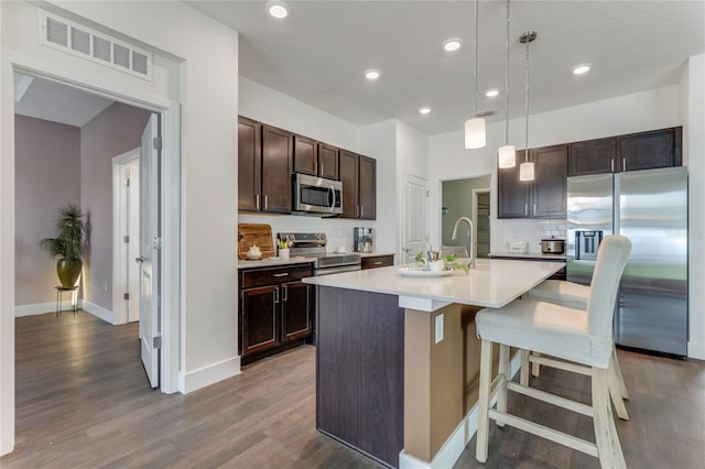 kitchen with dark wood-style flooring, visible vents, light countertops, appliances with stainless steel finishes, and dark brown cabinets