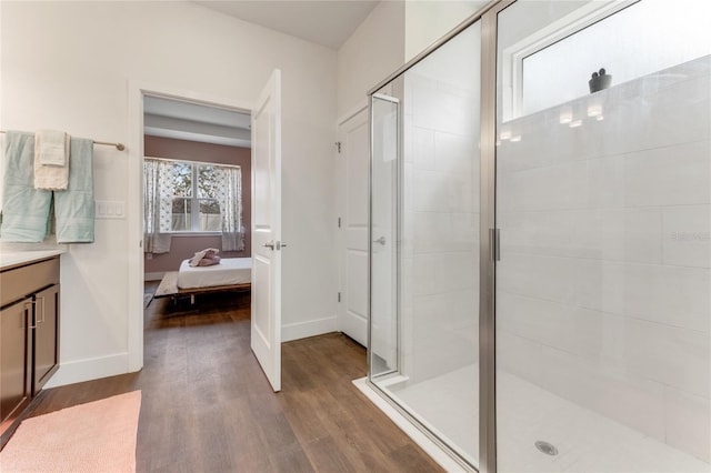 ensuite bathroom with baseboards, ensuite bath, wood finished floors, vanity, and a shower stall