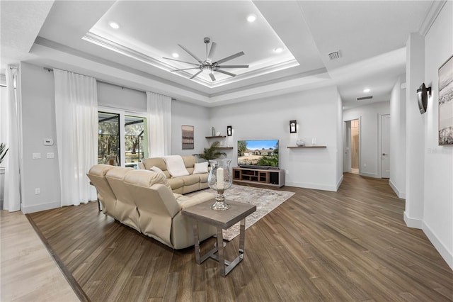 living room featuring recessed lighting, a raised ceiling, baseboards, and wood finished floors