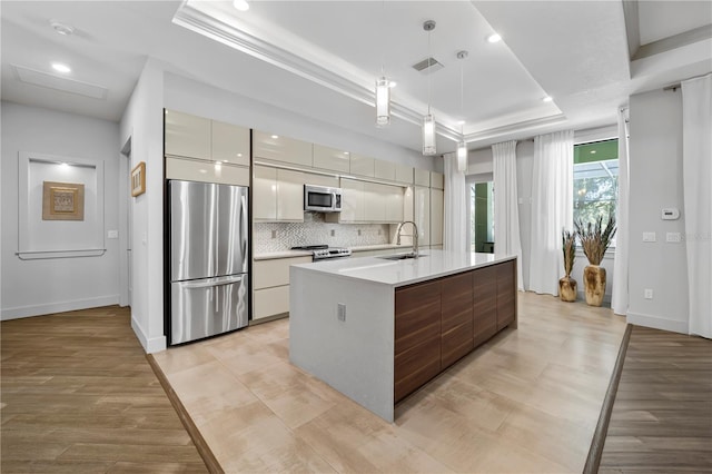 kitchen featuring a sink, visible vents, appliances with stainless steel finishes, a tray ceiling, and modern cabinets