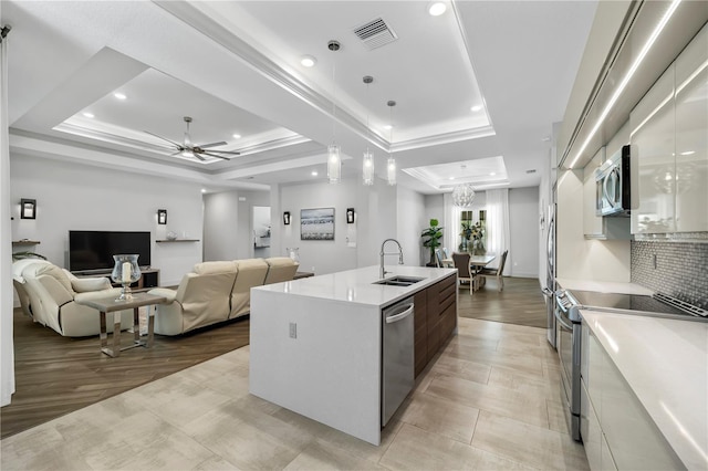 kitchen featuring visible vents, appliances with stainless steel finishes, a tray ceiling, light countertops, and a sink