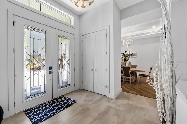 foyer with a chandelier, french doors, baseboards, and light wood finished floors