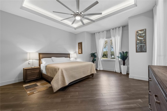 bedroom featuring ceiling fan, baseboards, a raised ceiling, and dark wood-style flooring