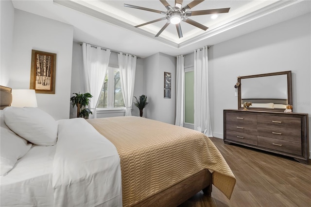 bedroom featuring ceiling fan, a raised ceiling, and wood finished floors