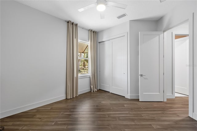 unfurnished bedroom with baseboards, visible vents, dark wood-style floors, ceiling fan, and a closet