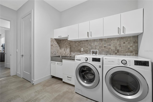 washroom with light wood-style flooring, a sink, baseboards, washer and dryer, and cabinet space